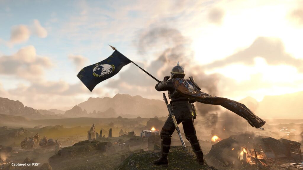 Helldivers 2 Ironclad Democracy Warbond Launches September 22 Official Helldivers 2 promotional image showing a Helldiver planting the Super Earth flag over a burning battlefield at