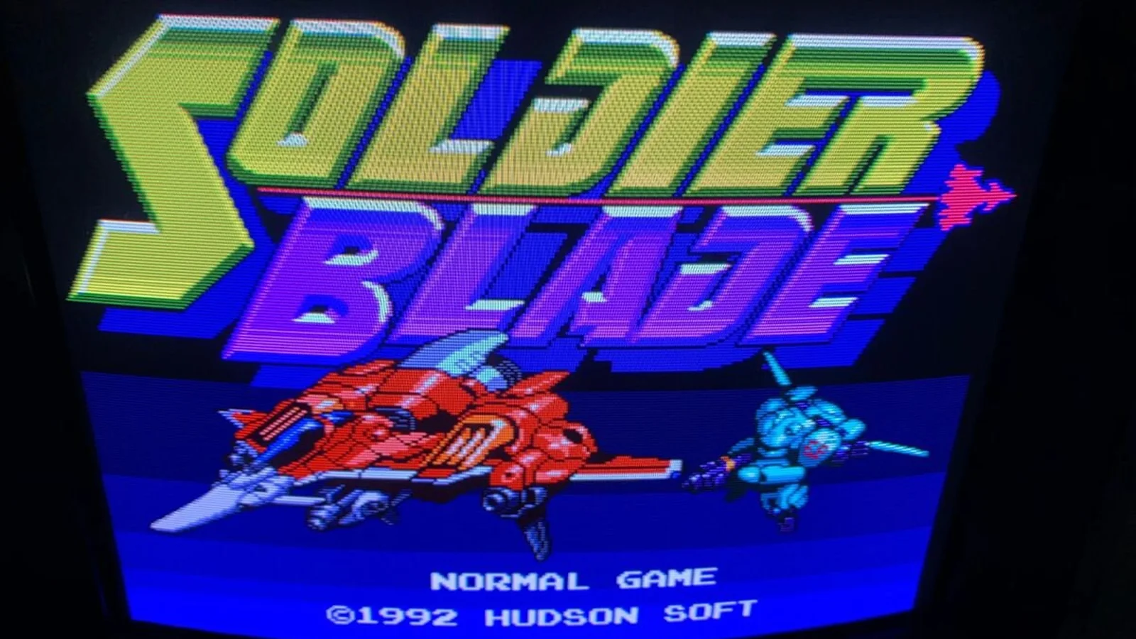 Soldier Blade title screen displayed on a CRT, with the game's red fighter and Hudson Soft branding