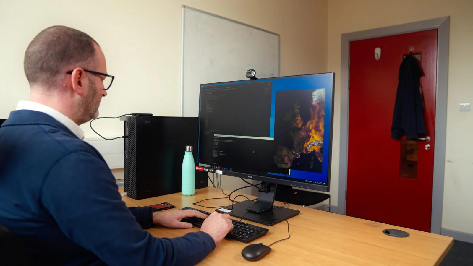 Researcher working at a desktop system with a UK pollution visualization displayed on screen