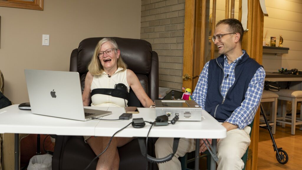 Official Paradromics photograph showing the first long-term Connexus participant using the BCI system at home with a