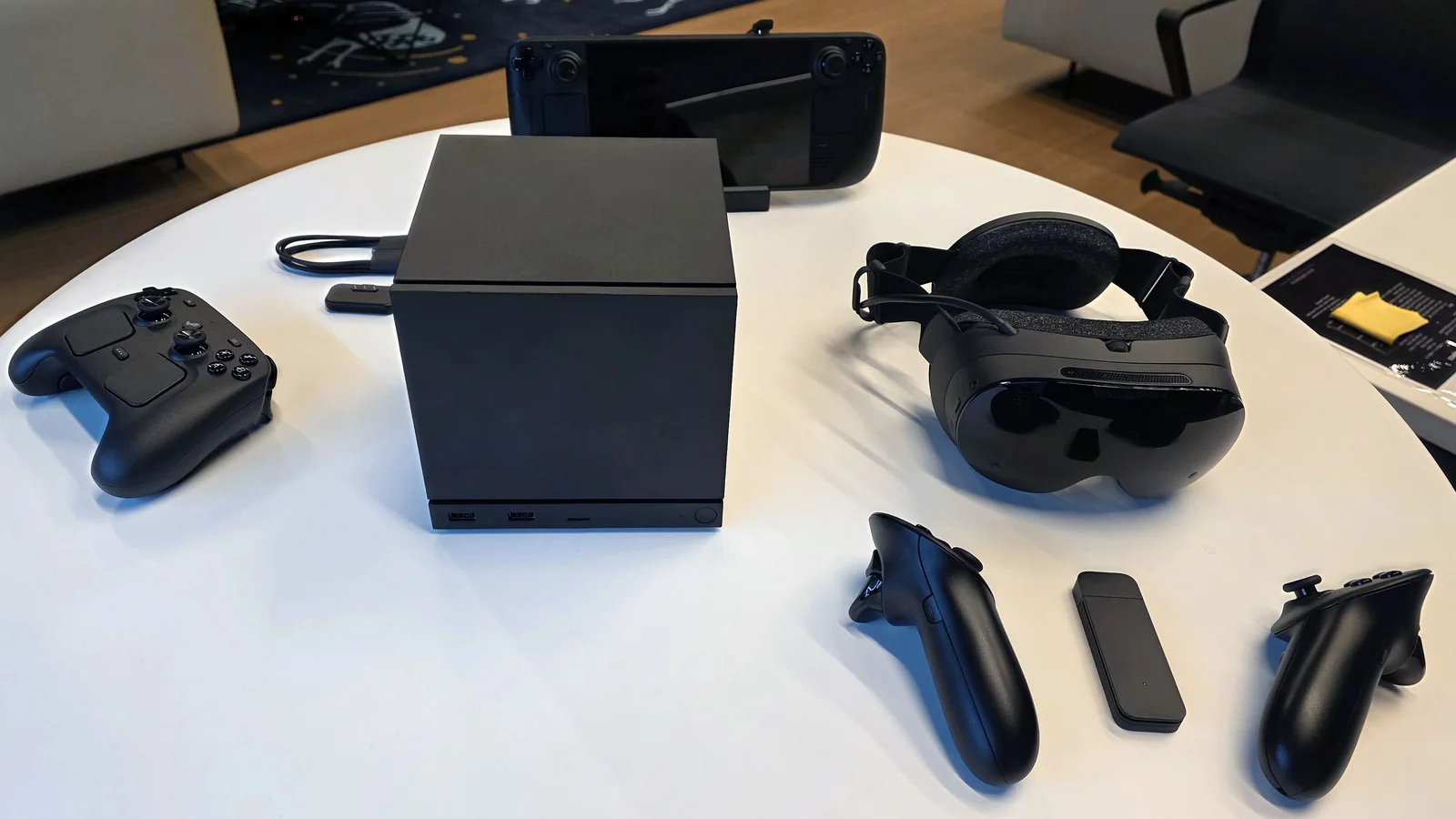 Hands-on photograph showing the Steam Frame headset, both controllers and its wireless adapter alongside Valve's other