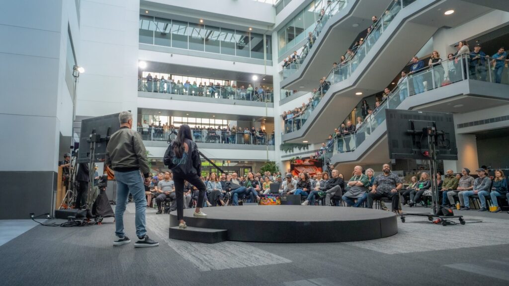 Xbox Reportedly Preparing Hundreds of Layoffs and Studio Consolidation Xbox employees gathered inside a large Microsoft office atrium for an internal presentation