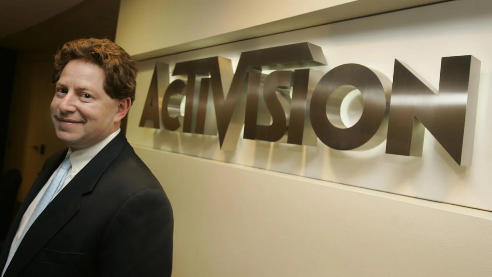 Bobby Kotick standing beside a large Activision logo