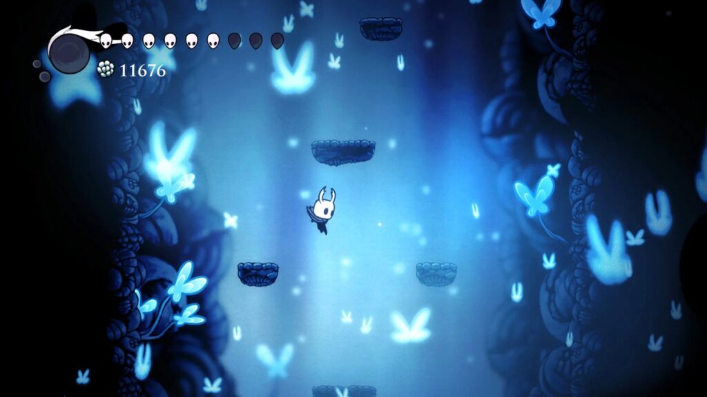 Official Hollow Knight gameplay screenshot showing The Knight moving through a luminous blue cavern filled with glowing