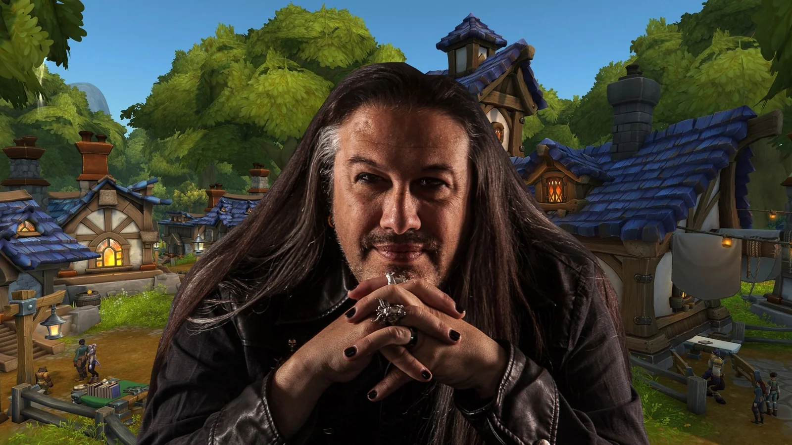 John Romero smiling at a vintage gaming workstation, wearing a black shirt patterned with skulls and roses