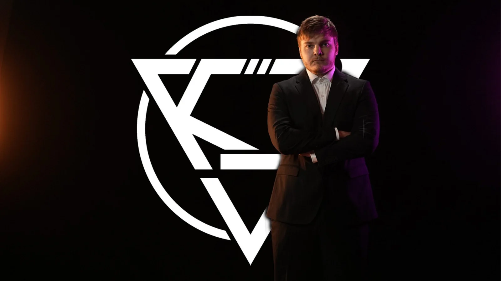 Cyanide posing in a formal black suit with crossed arms against a dark background featuring KOVA Esports branding
