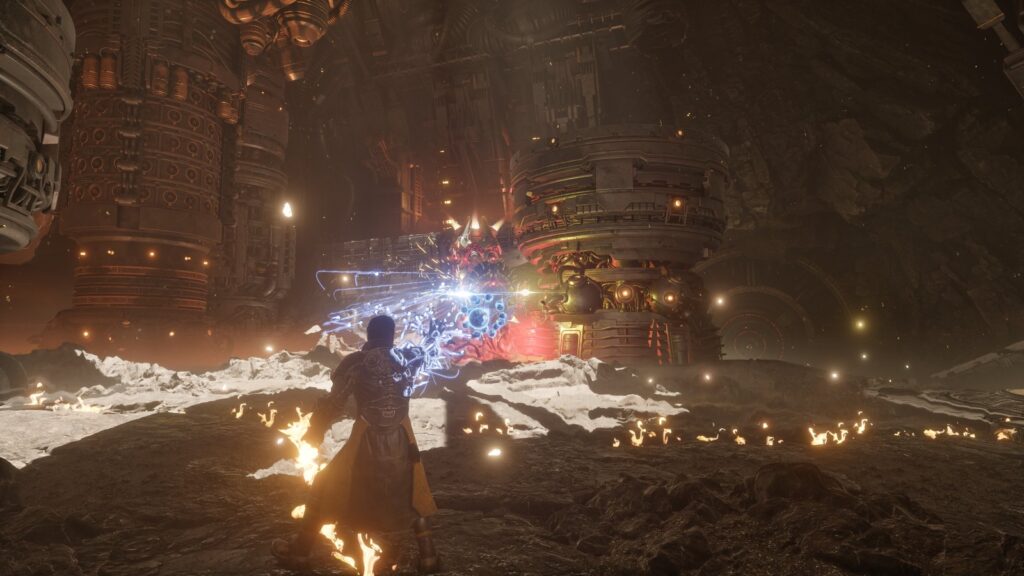 Arjun Devraj battles enemies with blue energy projectiles and explosions inside a massive industrial environment