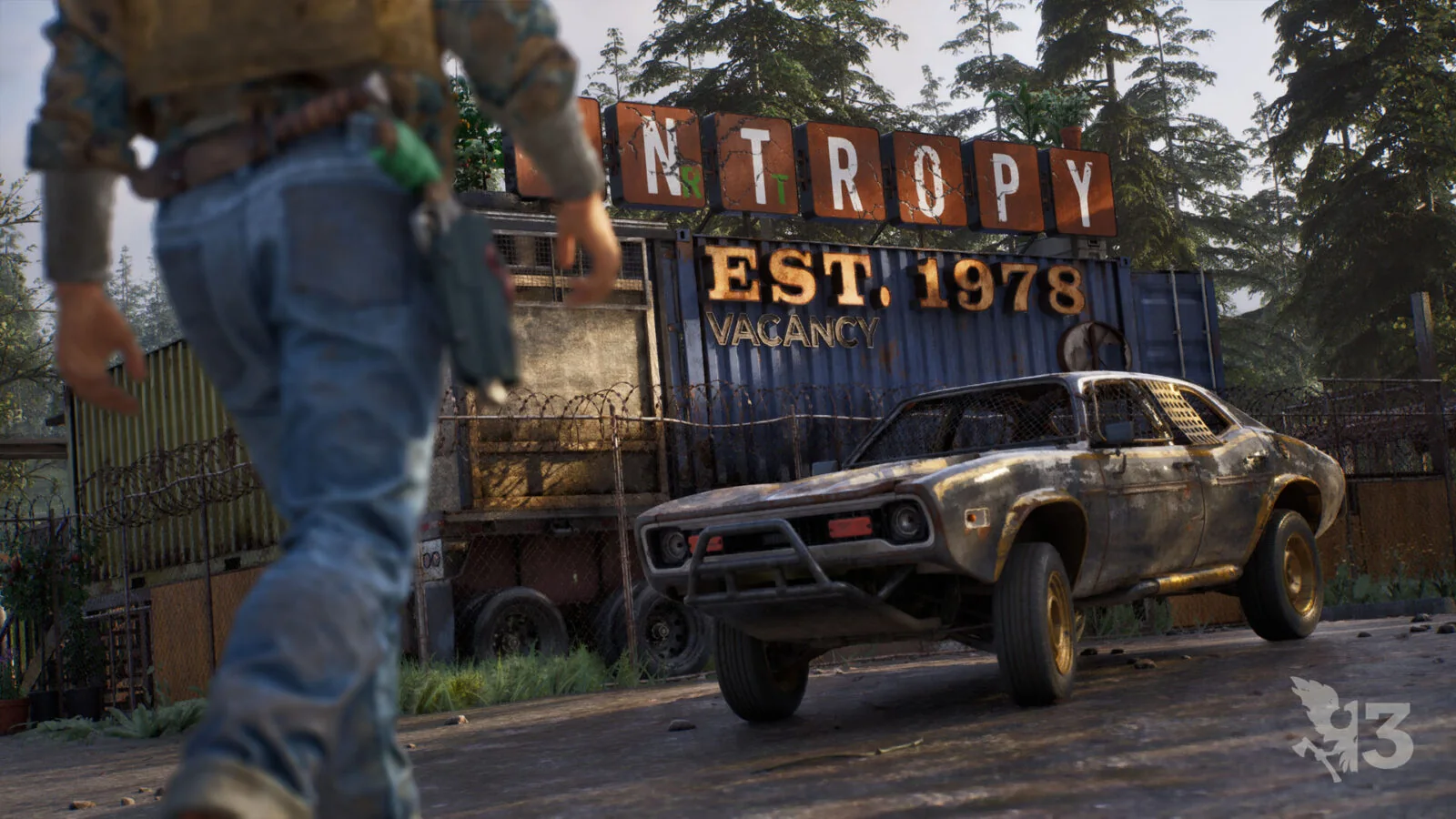 Official State of Decay 3 screenshot showing an armed survivor walking past a wooden building with another survivor
