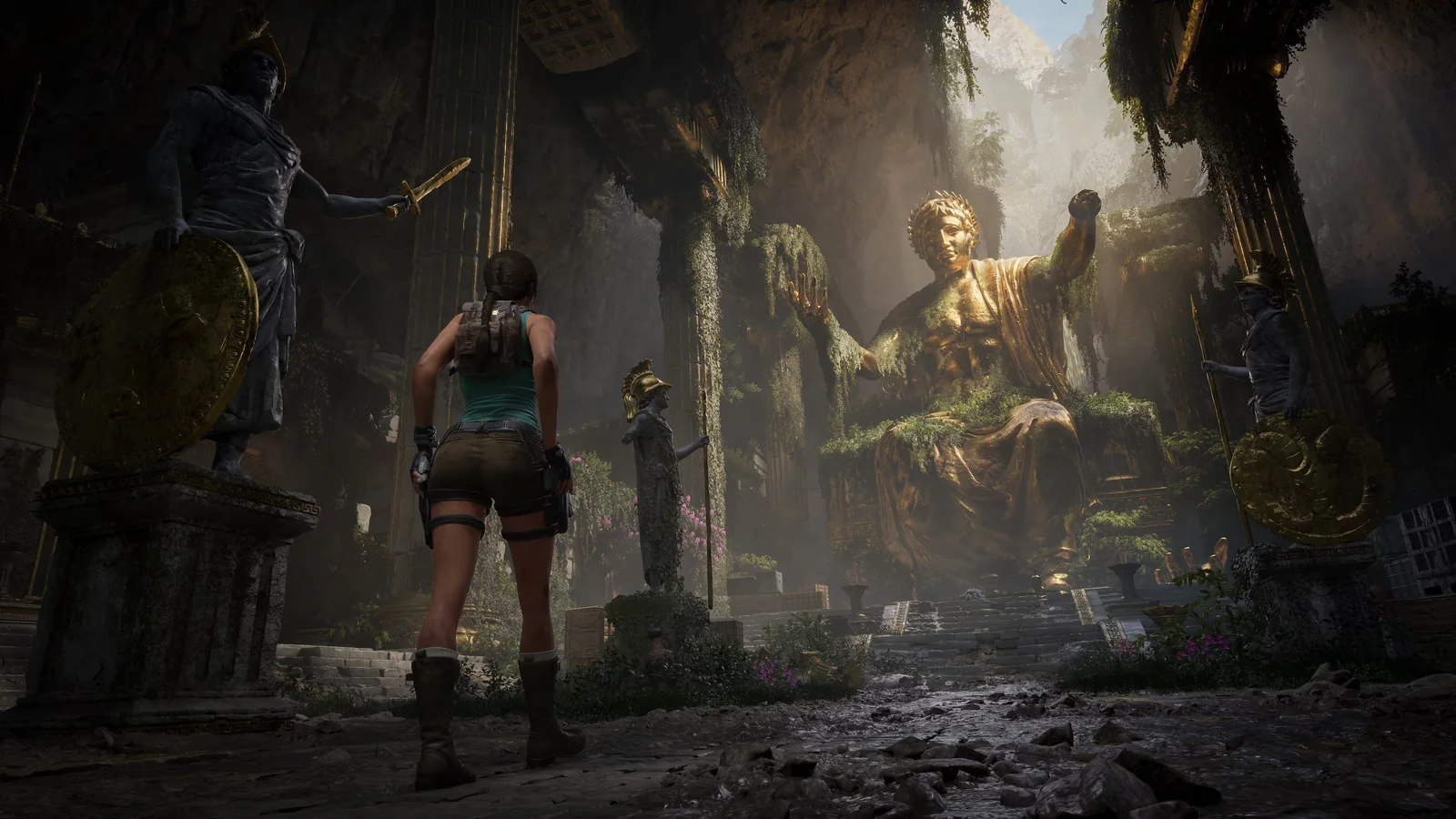Lara Croft stands inside a dimly illuminated Greek temple surrounded by statues and ancient architecture