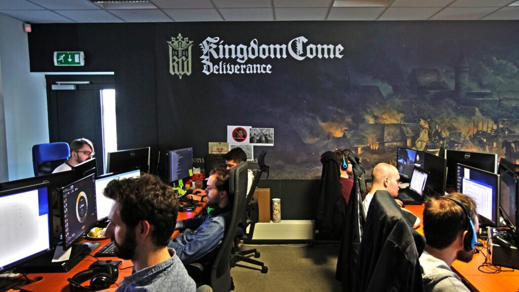 Warhorse Studios Confirms Cyberattack and Company Data Breach Warhorse Studios development office showing employees working at computers beneath a Kingdom Come: Deliverance mural